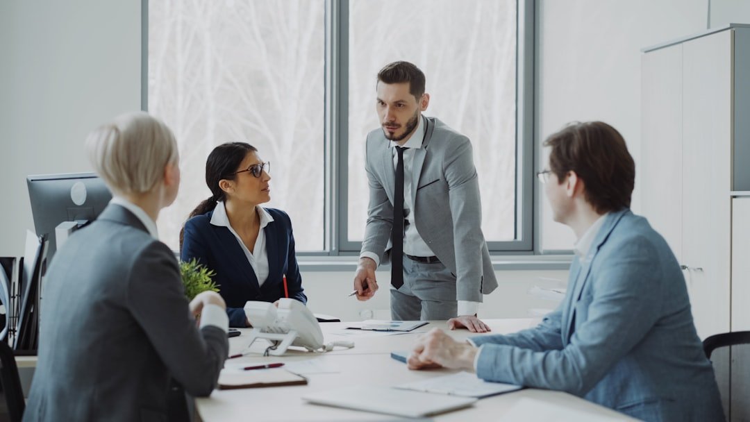 About Businesswoman discussing reports with male and female colleagues sitting at the table in modern office indoors